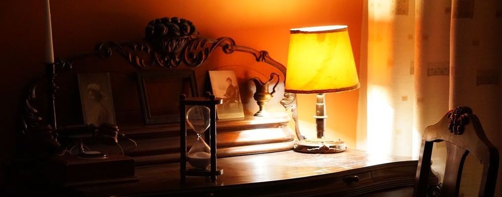 Poveste Code2Connect - clepsidră, lampă și fotografii vechi pe o comodă